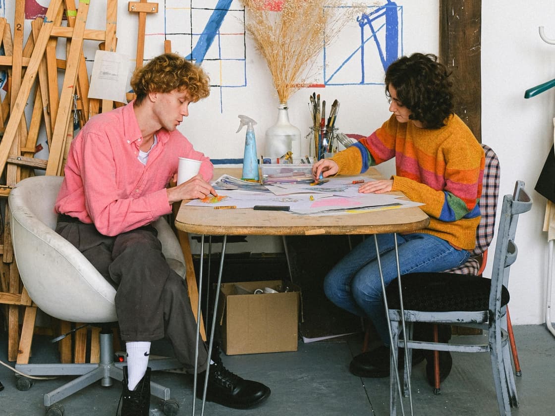 Two people working through sketches together at a studio table